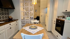 A kitchen with white cabinets, a wooden table, and a white chair. - Casa del Mare Sicily Letojanni  (Letojanni)
