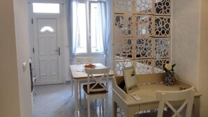 A dining area with a table and chairs, a laptop, and a decorative vase with a flower. - Casa del Mare Sicily Letojanni  (Letojanni)