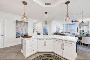 A spacious kitchen with white cabinetry, a central island, and pendant lighting. - Waterfront 2BR @ The Pass • Sleeps 6 • Bay Views, Pools & Beach Access (Orange Beach)
