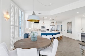 Una cocina moderna con muebles blancos, una isla central e iluminación colgante.