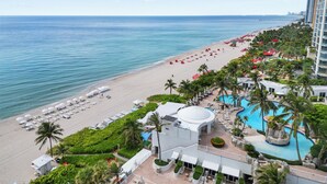 A resort with a beach, pool, and palm trees. - LUXURIOUS APARTMENT FRONT OF THE BEACH IN SUNNY ISLE (Sunny Isles Beach)