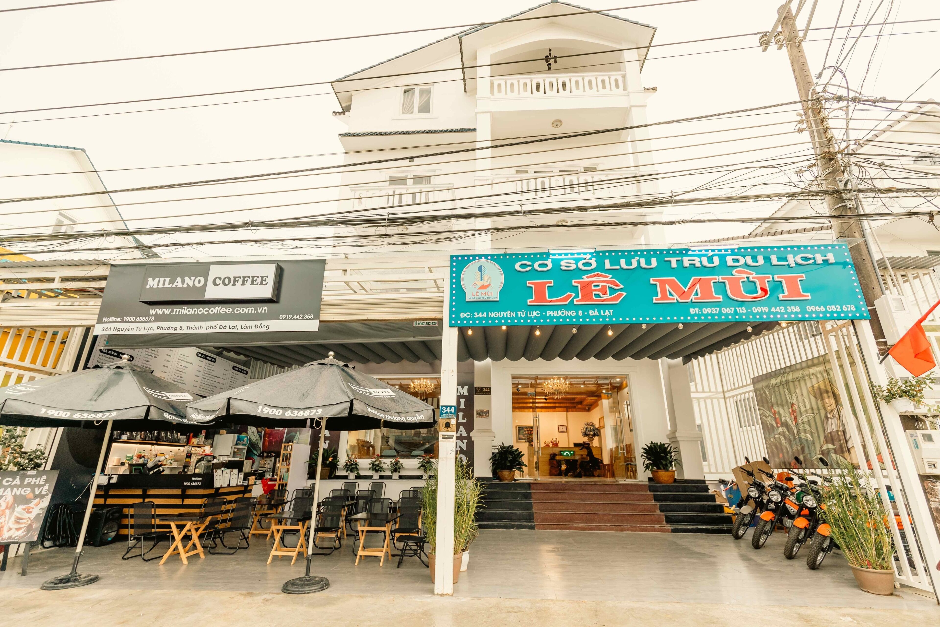 Una cafetería llamada MILANO COFFEE con terraza y un letrero que dice LE MUI.