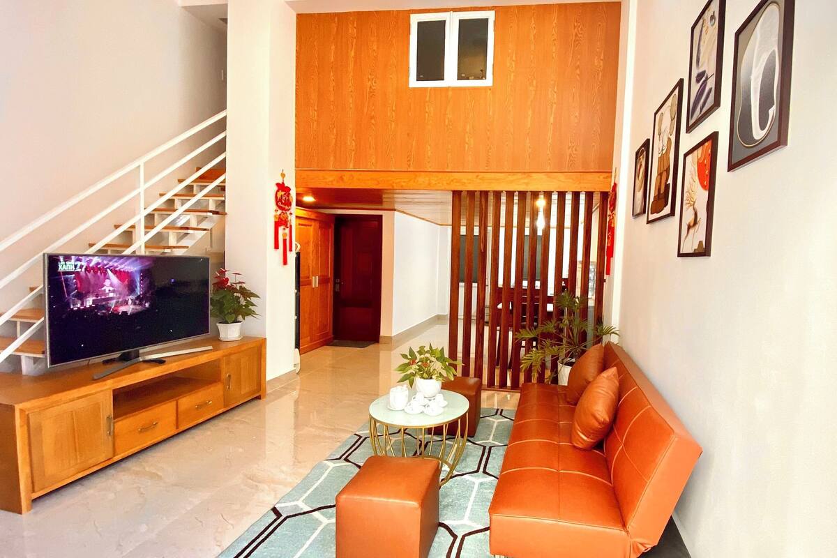 A modern living room with a sofa, TV, and a staircase.