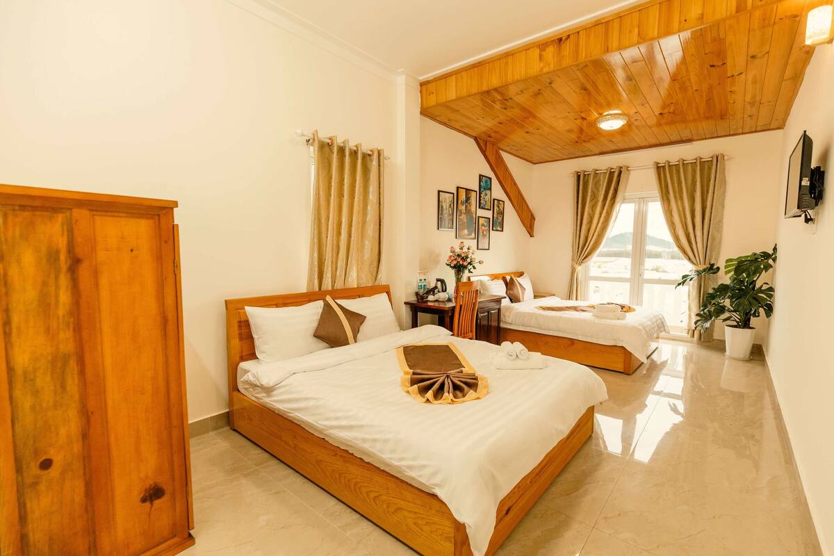 A bedroom with two beds, wooden ceiling, and a large wardrobe.