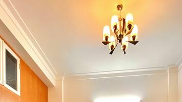 A living room with a sofa, two ottomans, a coffee table, and a chandelier. There are four framed pictures on the wall.