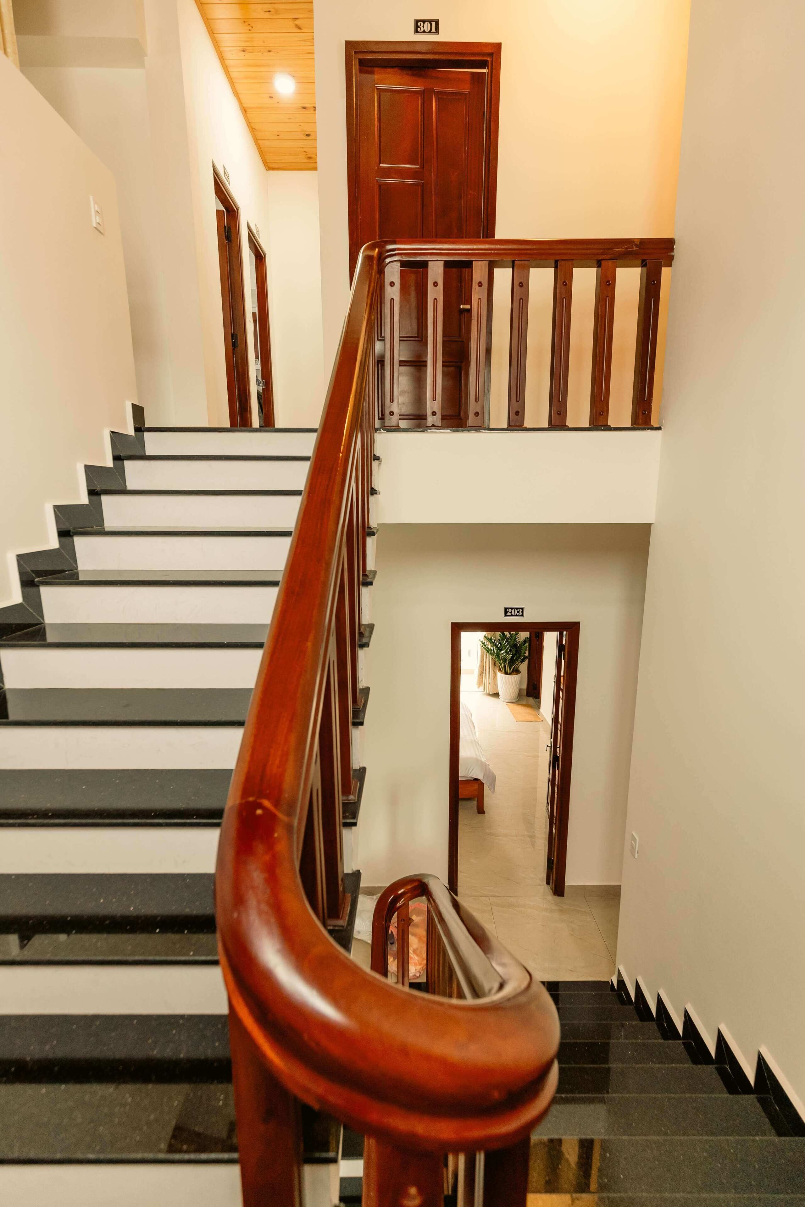 A staircase with wooden handrails and black steps, leading to a door marked 301.