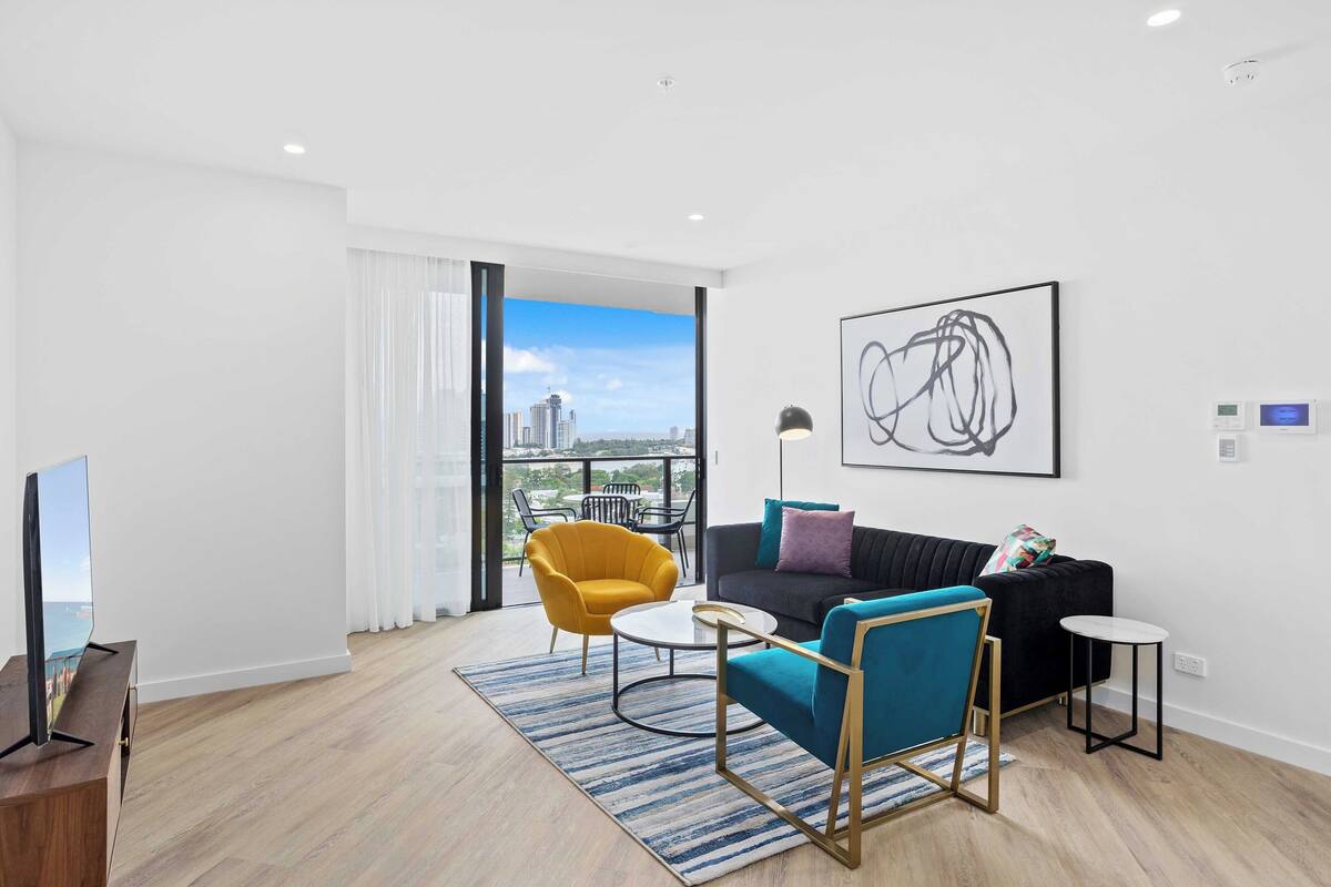 A modern living room with a sofa, armchairs, a coffee table, and a TV.