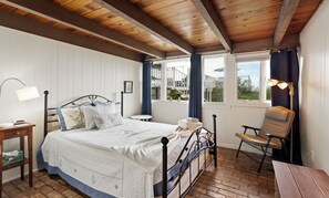 A bedroom with a bed, bedside table, lamp, chair, and windows with curtains. - B30: Pet friendly stay on Lake Michigan | Relax & Unwind (Spring Lake)