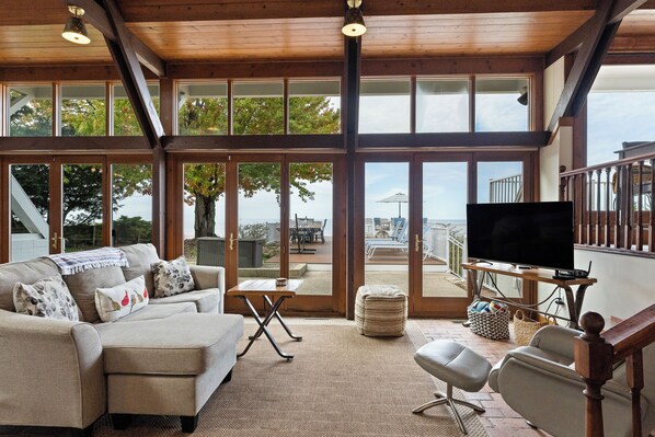 A spacious living area with a large window, a sofa, a television, and a view of the outdoors.