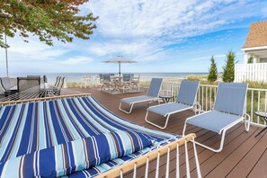 A deck with a hammock, lounge chairs, and a table with an umbrella, overlooking a body of water. - B30: Pet friendly stay on Lake Michigan | Relax & Unwind (Spring Lake)