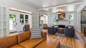 Uma sala de estar ampla com um sofá de couro marrom, poltronas azuis e uma lareira.