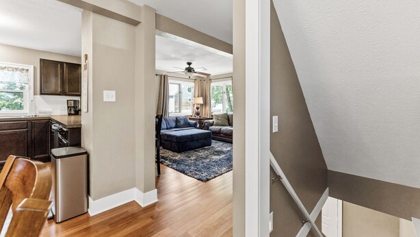 A modern kitchen with wooden cabinets, a dishwasher, and a dining area with a wooden table and chairs. - Captain's Corner | Walk to Beach, Relax by the Lake (Spring Lake)