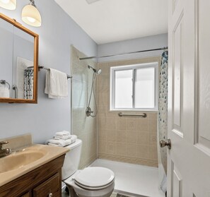Un baño con ducha, inodoro, lavabo y ventana.