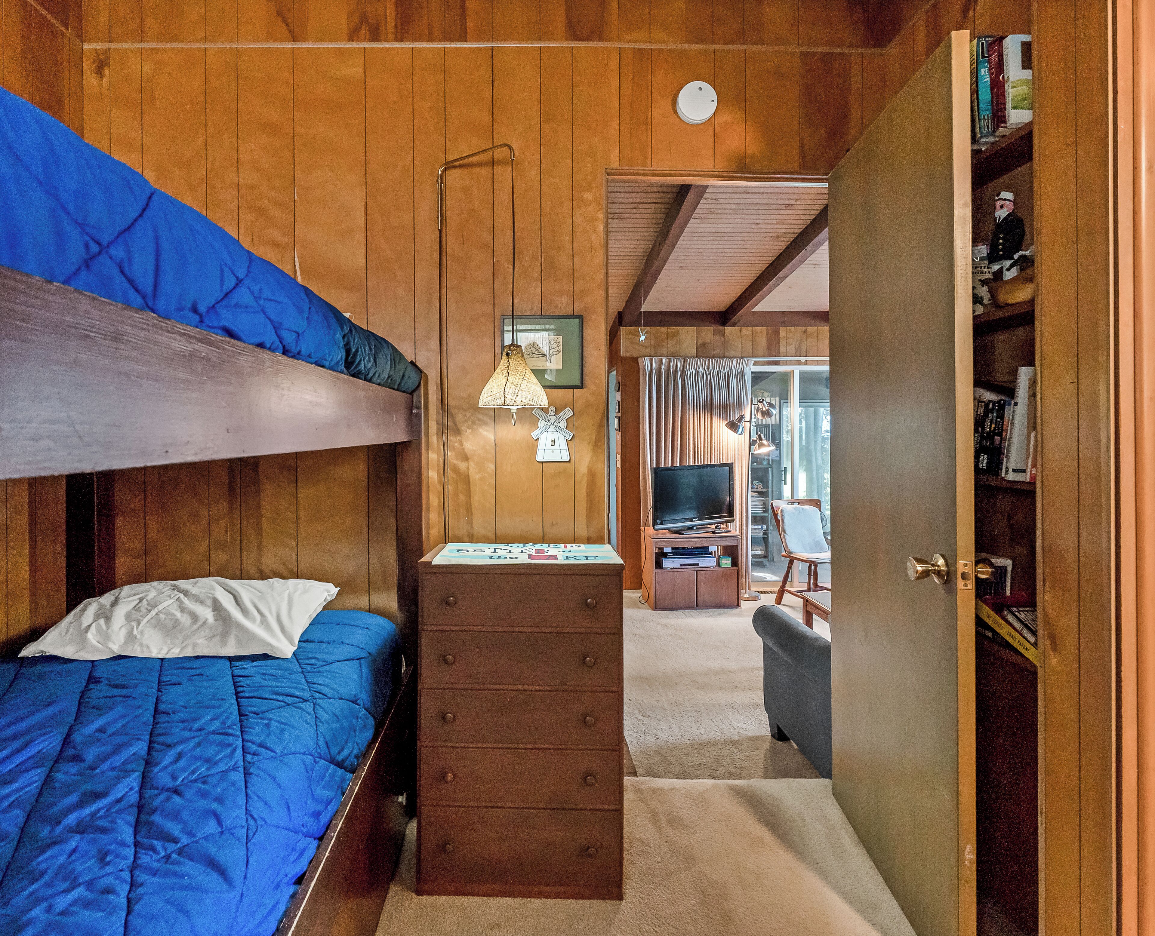 A room with a bunk bed, a dresser, a desk with a computer, and a bookshelf.