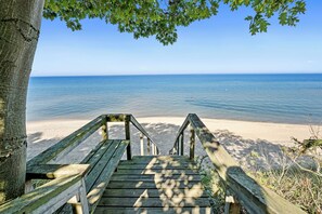 A wooden staircase leading to a beach with clear blue water and a sandy shore. - Private Lake Michigan Beach Access (Holland)