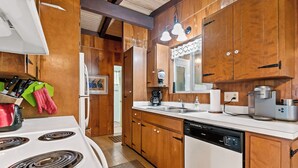 A kitchen with wooden cabinets, a white stove, a dishwasher, and a coffee maker. - Private Lake Michigan Beach Access (Holland)