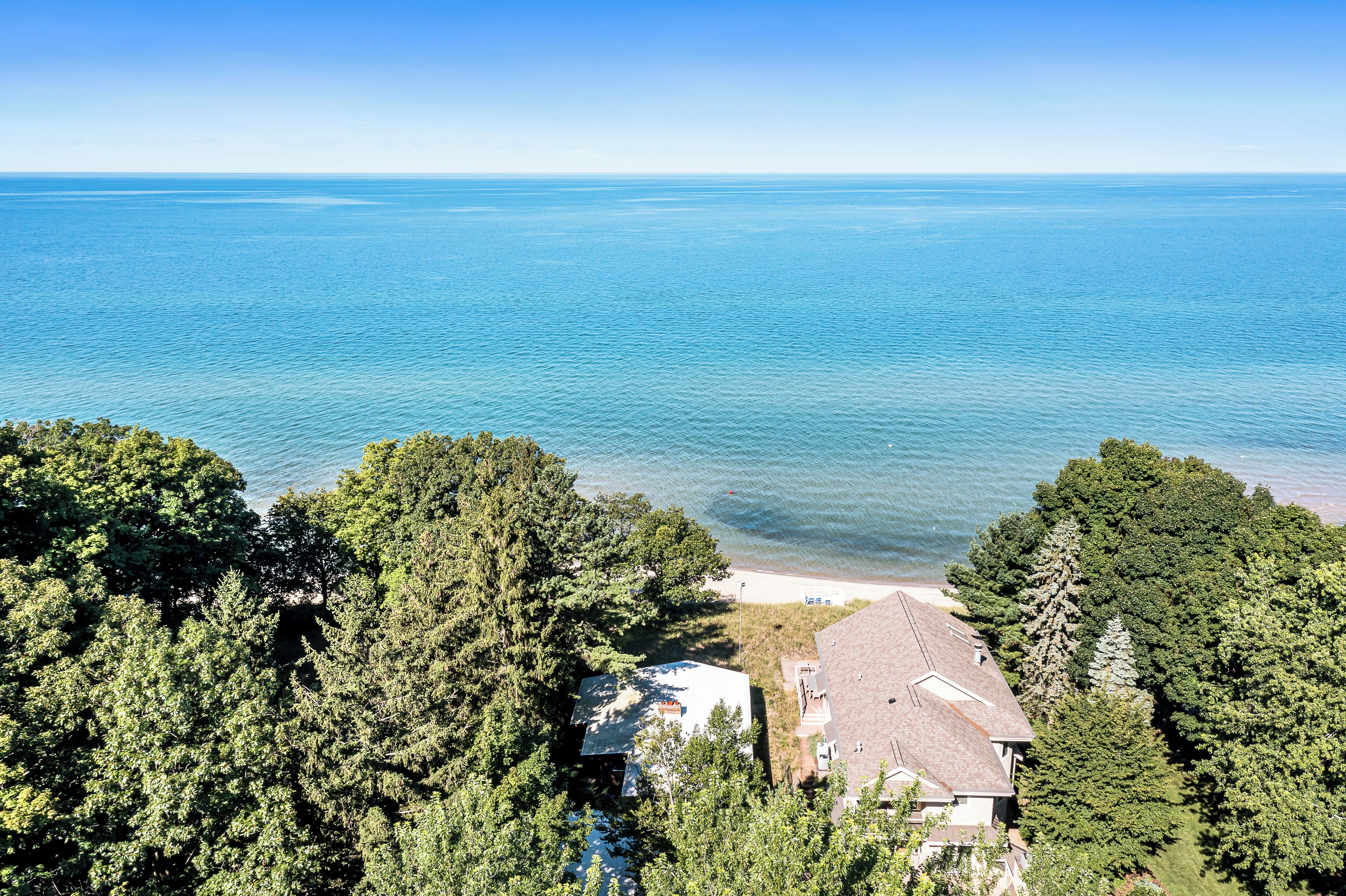 Eine Luftaufnahme eines Küstengrundstücks mit dichtem Wald, einem Strand und freiem Blick auf den Ozean.