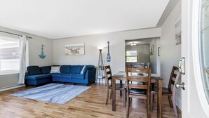 A living room with a blue sofa, wooden dining table, and chairs. - Private pool, close to Lake Michigan Beaches (Muskegon)