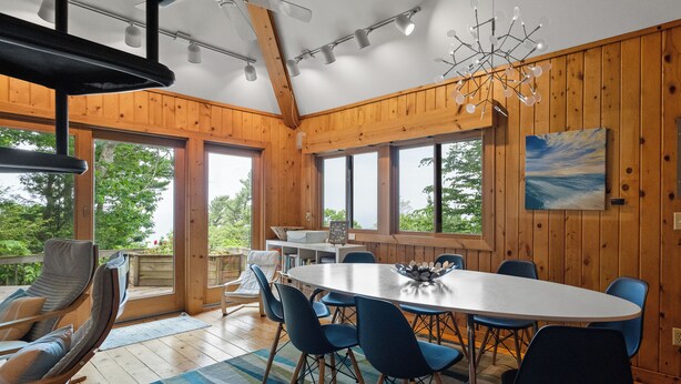 A dining area with a large table, blue chairs, and a view of the outdoors.
