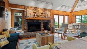 A cozy cabin interior with a stone fireplace, wooden walls, and a comfortable seating area.