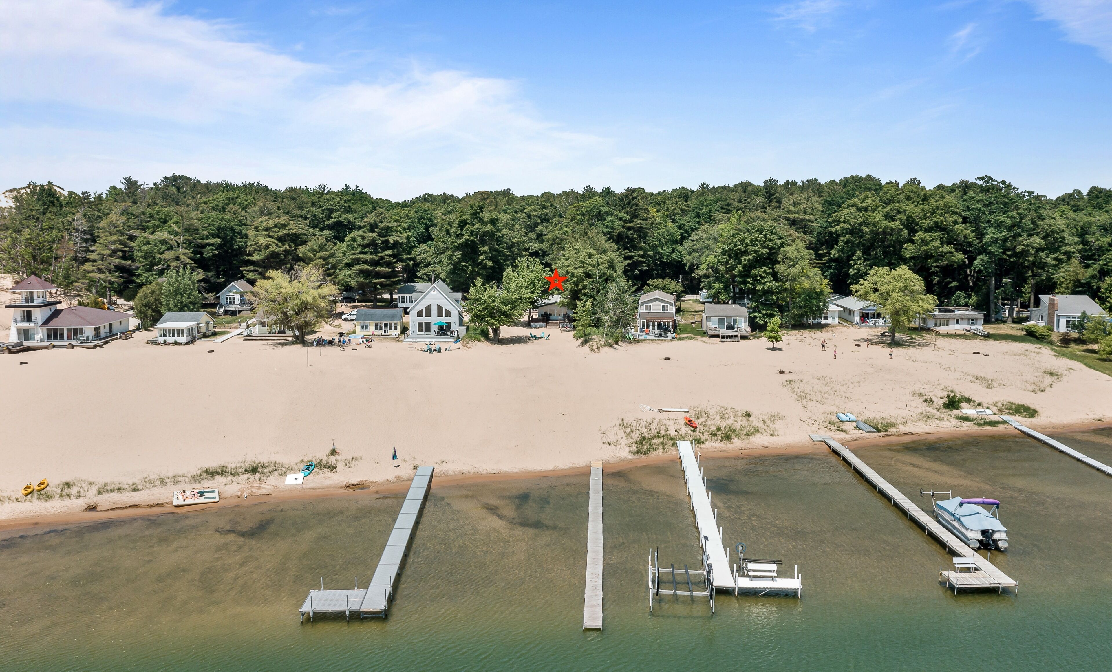 A coastal area with houses, a sandy beach, and a dock extending into the water.