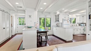 A spacious kitchen with white cabinetry, a dining area with a table and chairs, and a large window providing natural light.