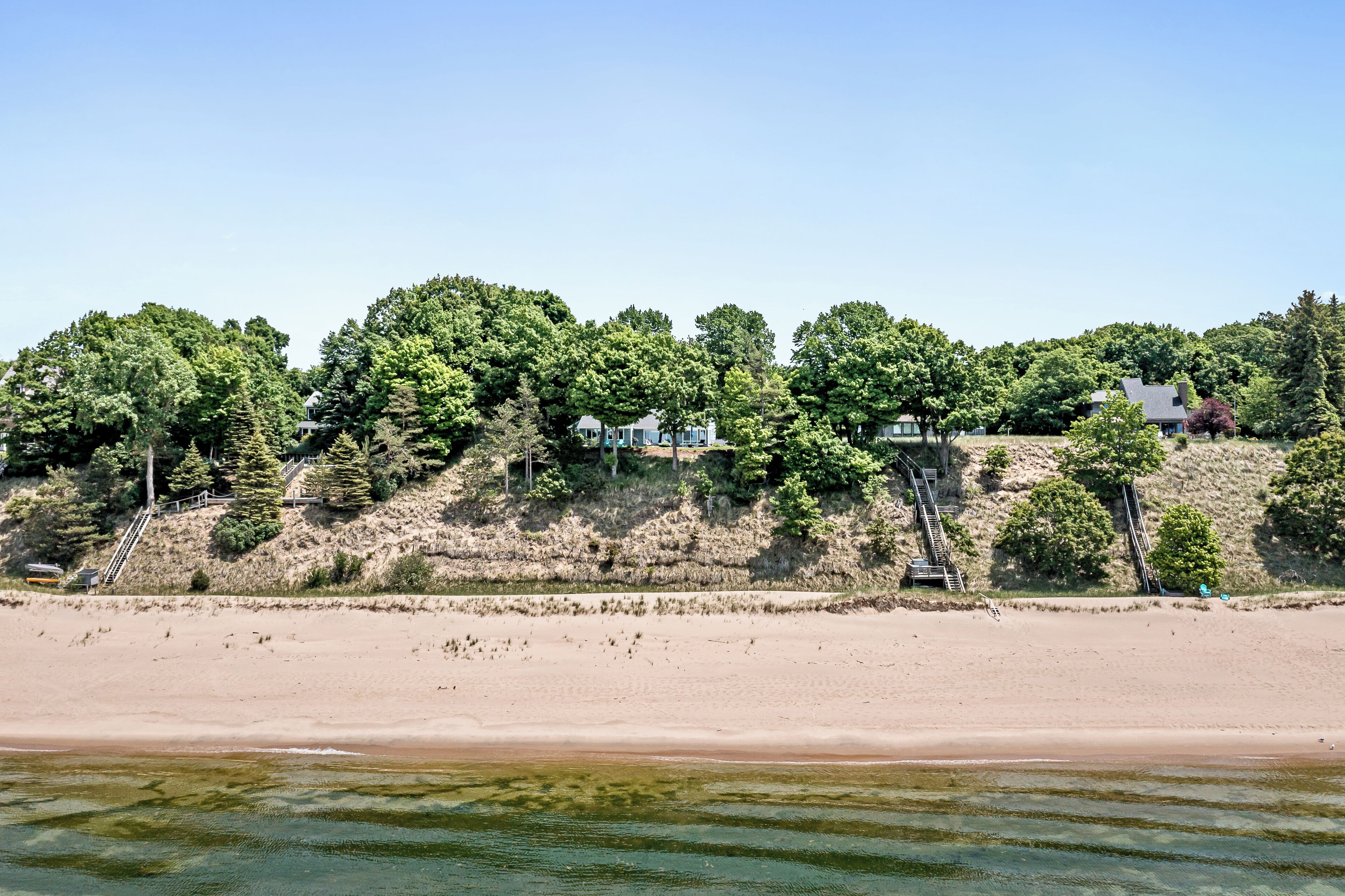 Une plage avec un escalier menant à une colline où se trouvent des maisons.