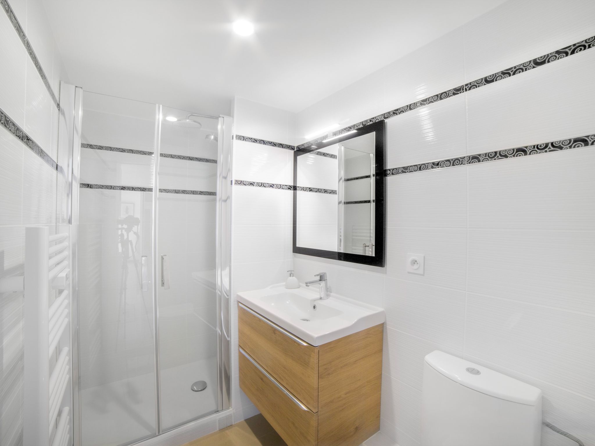 Une salle de bain moderne avec une douche à parois de verre, un meuble-lavabo en bois avec un lavabo blanc et des toilettes.