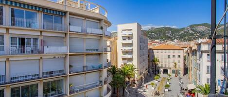Un immeuble à plusieurs étages doté de balcons, d’une cour intérieure et offrant une vue sur la ville et les montagnes environnantes.