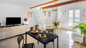 Una cocina moderna con comedor, televisor y escalera que sube a un nivel superior.