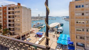 Un puerto deportivo con barcos amarrados, un edificio grande de diseño moderno y vistas al agua.