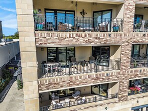 Un immeuble à plusieurs étages doté de balcons, d’un espace extérieur aménagé pour s’asseoir et de plantes en pot.