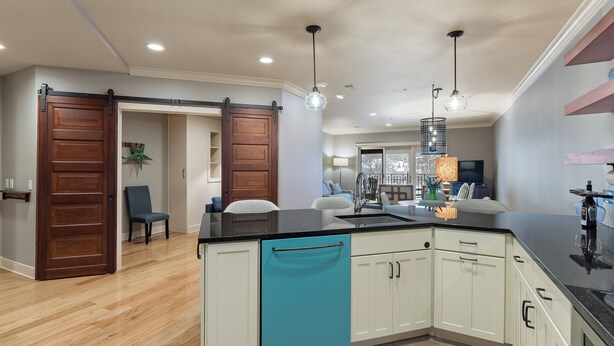 A kitchen with a black countertop, white cabinets, and a teal dishwasher. - Downtown Grand Haven Stay | Spacious 2-Bed in Former Theatre (Grand Haven)