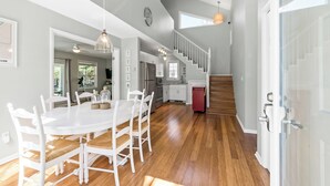 A spacious kitchen with white cabinets, a dining table with chairs, and a staircase leading to an upper level.