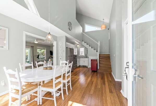 A spacious kitchen with white cabinets, a dining table with chairs, and a staircase leading to an upper level.