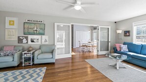 A spacious living room with hardwood floors, a ceiling fan, and a large window.