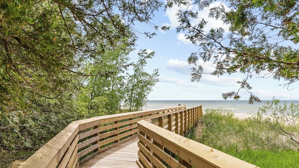 A wooden boardwalk leading to a beach, surrounded by trees and vegetation.