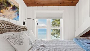 Een slaapkamer met een bed, een raam en een schilderij aan de muur.