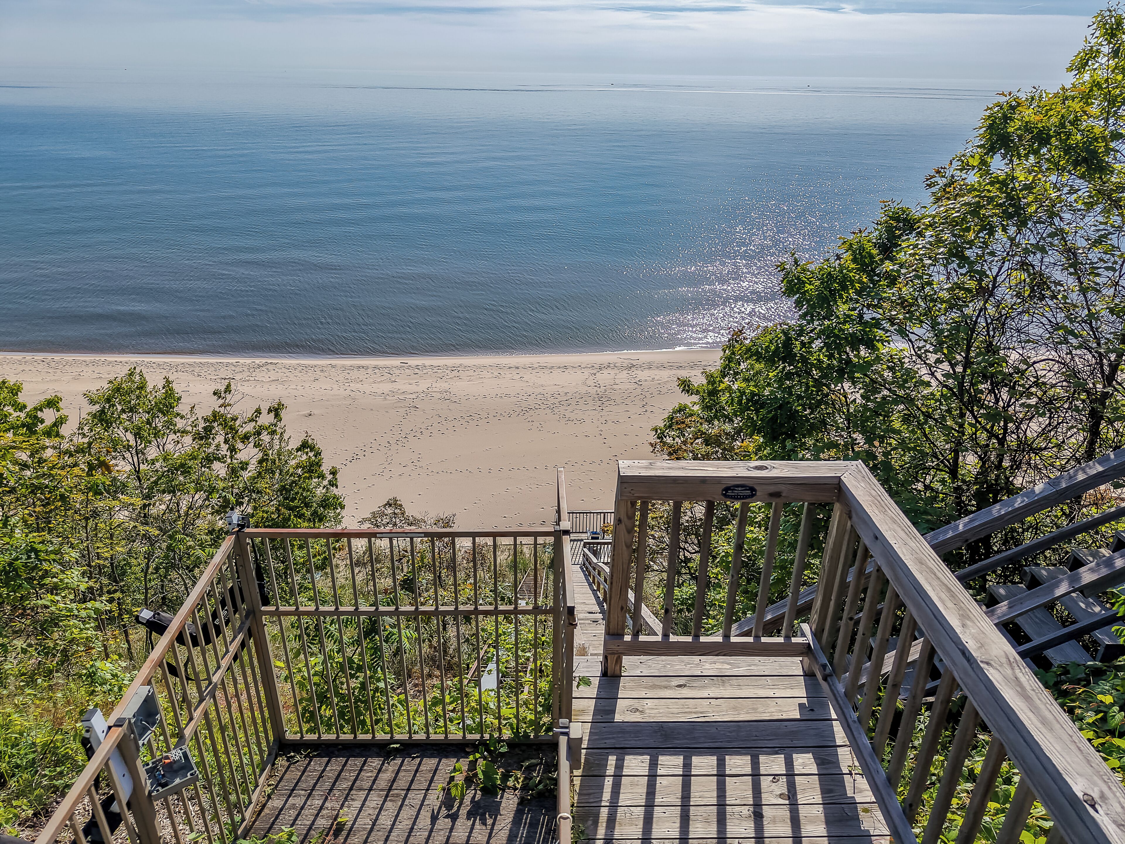 A wooden staircase leading to a beach with a railing and a sign.