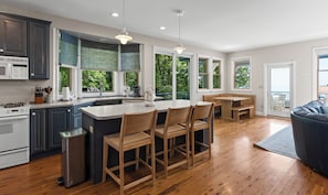 Una cocina moderna con una isla central, sillas de madera y ventanas amplias.