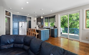 Una cocina moderna con armarios azules, una isla central y un comedor con sillas de madera.