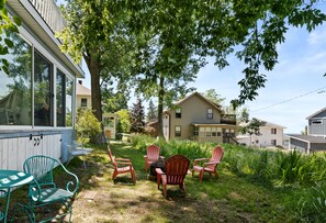 A backyard with a table and chairs, a small tree, and a house in the background. - Rest-A-While: Spacious 4-Bedroom Retreat in Grand Haven (Grand Haven)