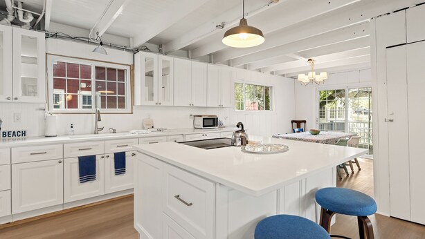 A modern kitchen with white cabinetry, a large island, and a view to the outside.