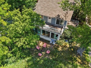 A two-story house with a balcony, surrounded by dense greenery. - Rest-A-While: Spacious 4-Bedroom Retreat in Grand Haven (Grand Haven)