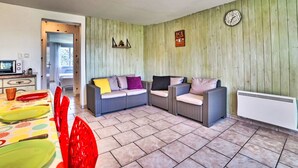 Un salón acogedor con un conjunto de sofás, una mesa de comedor con platos coloridos y un reloj en la pared.