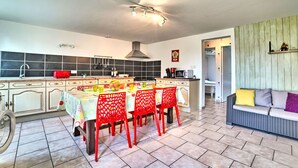 Una cocina moderna con una isla central, sillas rojas y una mesa de comedor preparada para cuatro.