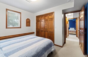 A bedroom with a bed, wooden wardrobe, and a hallway leading to another room.