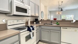 Cozinha moderna com eletrodomésticos brancos, uma ilha grande e um lustre.