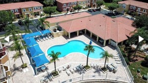 Um hotel com piscina, espreguiçadeiras e um terraço coberto.