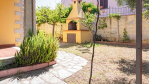 Un patio con un sendero de piedra, un árbol pequeño y un edificio con chimenea.